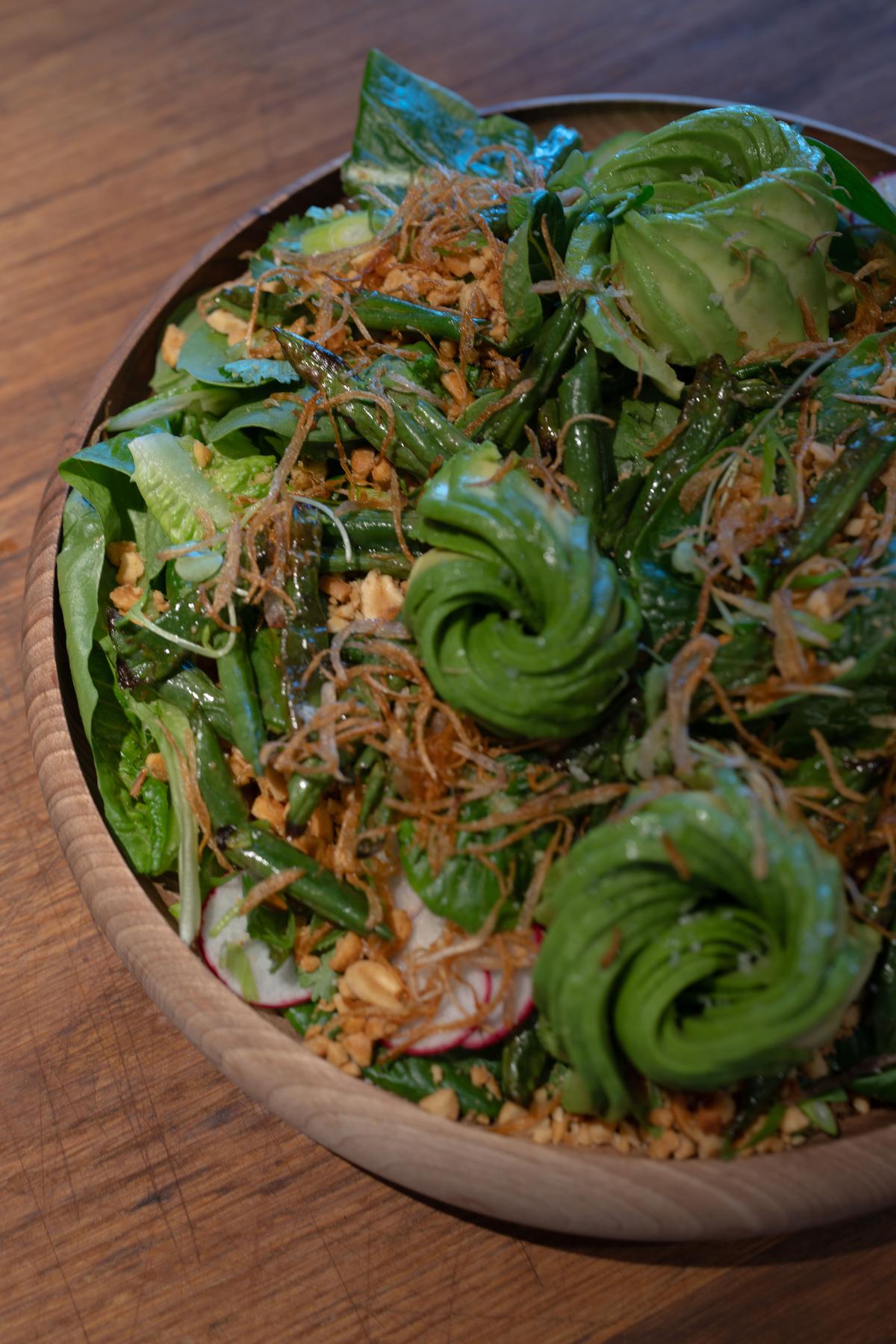 Garden salad with cucumber rosettes, radish and crispy shallot in a wooden bowl