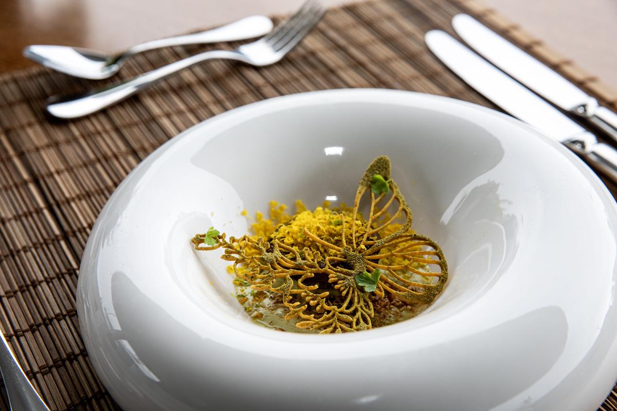 Signature amuse-bouche with a gilded tuile butterfly in a white ceramic bowl